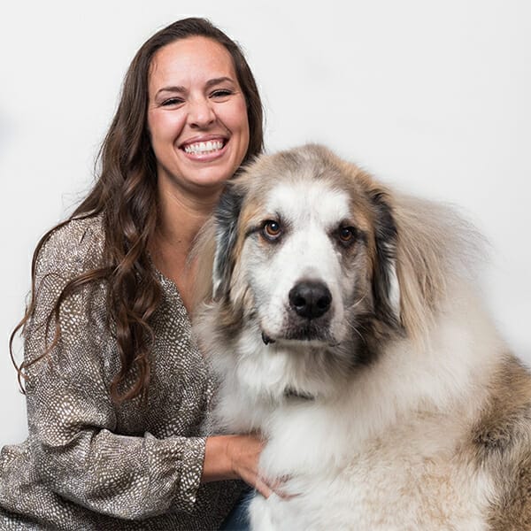 Board-Certified Small Animal Internal Medicine Specialist and Medical Director of MedVet Cincinnati, Dr. Jennifer (Jenny) Wells, hugging her giant white and grey pet dog
