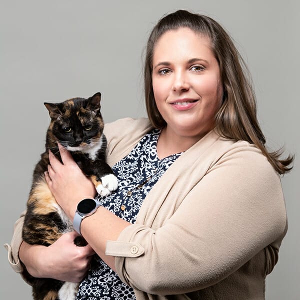 Board-Certified Small Animal Internal Medicine Specialist and Medical Director, Dr. Emily Klosterman, holding her calico pet cat and smiling