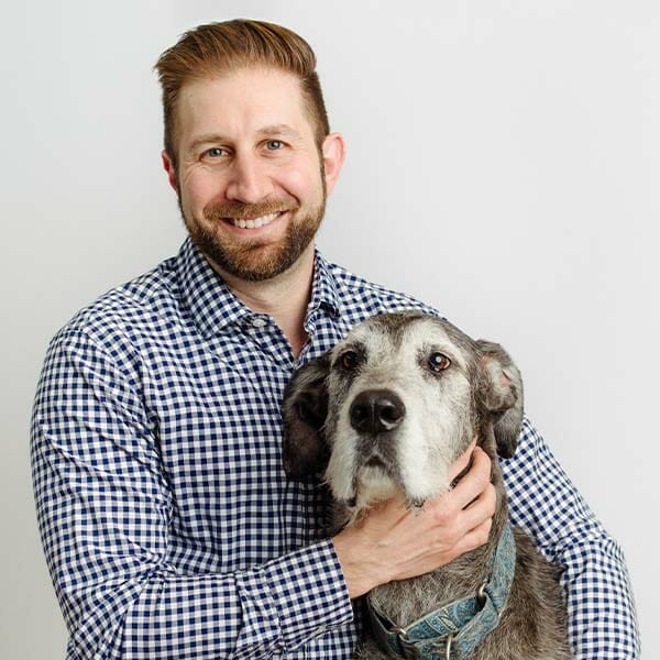 Emergency Medicine Veterinarian and Medical Director, Dr. Joseph Ielapi, holding his grey and white pet dog and smiling