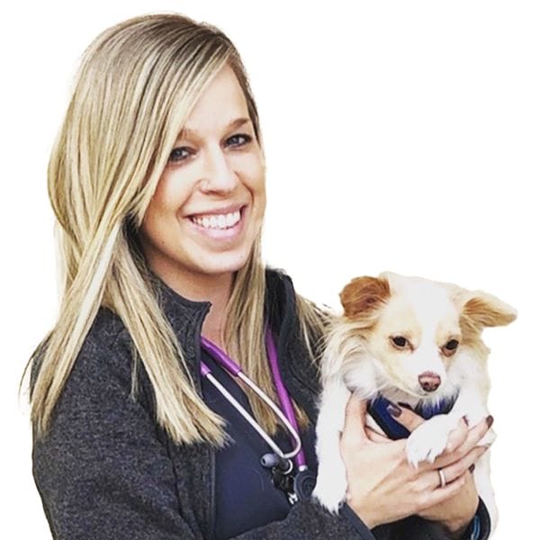 Hospital Director, Terra Schroop, smiling happily and holding her white dog.