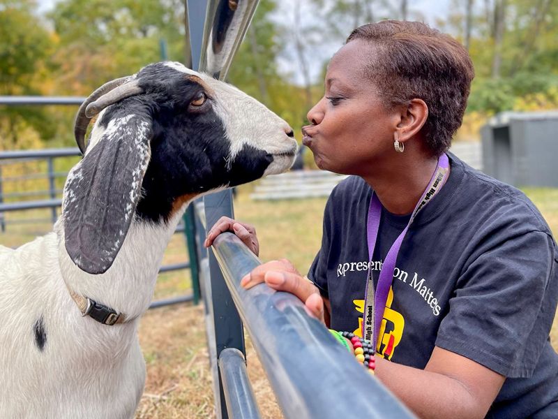 A MedVet team member kisses a goat at the zoo while attending the Black Employee Network outing