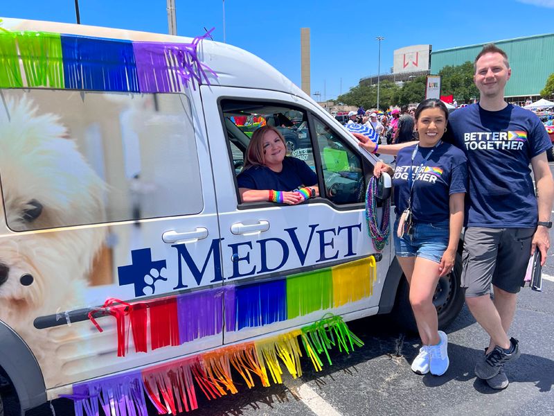 LGBTQ+ Employee Network team members pose next to MedVet Van for PRIDE parade